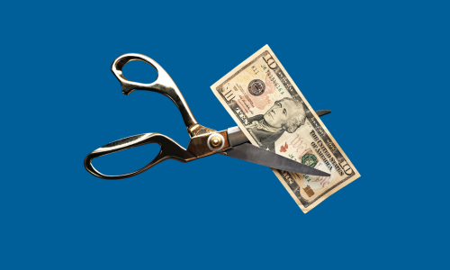 Scissors cutting money on blue background