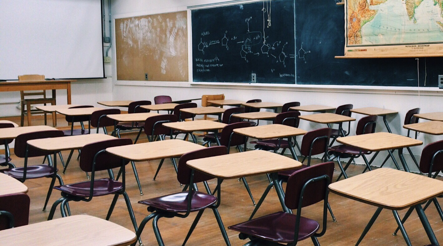 A classroom with rows of desks and chairs with chalkboard on the wall